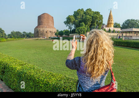 Eine Frau, die ein Bild der Dhamekh Stupa in Sarnath, Indien mit ihrem iPhone. Stockfoto