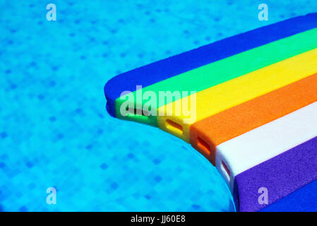 Regenbogen Muster Styropor schwimmen Board oder Fußleiste im Schwimmbadwasser, Sommer Urlaub Freizeitaktivität Objekt in der poolsid Stockfoto