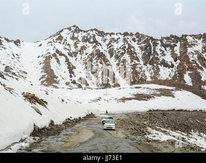 Ladakh, Indien - 18. Juli 2015. Touristischen Autos laufen auf gefährliche Straße mit Schneebergen in Leh, Ladakh, Indien. Ladakh ist das höchste Plateau im Zustand Stockfoto