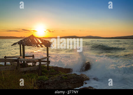 PAVILLON AM STRAND MIT DER SONNE DAHINTER Stockfoto