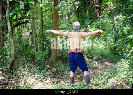 Asiatischer Mann Bauer trägt eine Gewehr Spaziergänge im Wald Hintergrund. Die Jagd und die Lebensweise der ländlichen Bevölkerung in Thailand-Konzept. Stockfoto