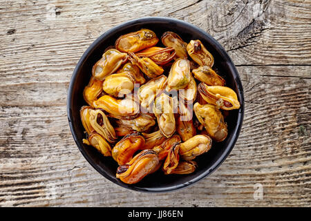 Schüssel mit marinierte Muscheln auf hölzernen Hintergrund, Ansicht von oben Stockfoto