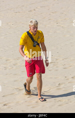 RNLI Rettungsschwimmer gehen auf Sand am Strand von Bournemouth, in Bournemouth, Dorset UK im Juli Stockfoto