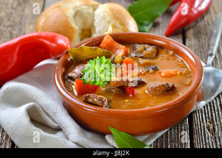 Heiße ungarische Gulaschsuppe serviert in einer Keramikschale mit einem frischen Wurf Stockfoto