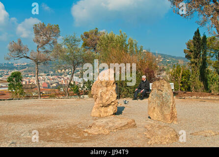 ältere Menschen spanischer Mann in seinen späten 60ern allein sitzen auf Bank im Park Güell Tauben füttern und genießen Ausblicke auf Barcelona an sonnigen Frühlingstag, Spanien Stockfoto