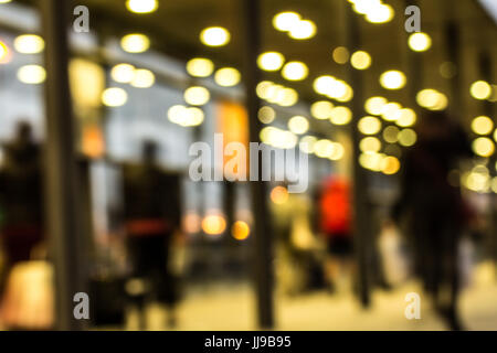 Abstraktion zeigt Passanten in einem Glaskorridor voller Lichter Stockfoto