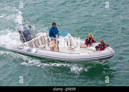 Mann und zwei Jungs in Cobra Inflatable Boat Bootfahren im Solent zwischen Lymington und Yarmouth, Isle Of Wight, Hampshire, UK im Juli Stockfoto