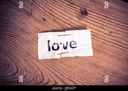 'Liebe' Wort geschrieben am zerrissen und geheftete Papier auf Holz Hintergrund Stockfoto