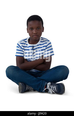 Porträt der traurige Junge saß am Boden vor weißem Hintergrund Stockfoto