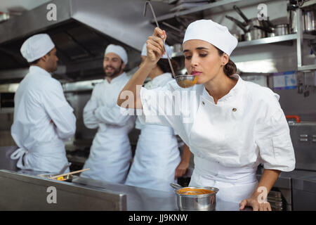 Koch schmeckendes Essen vom Löffel in Küche im restaurant Stockfoto