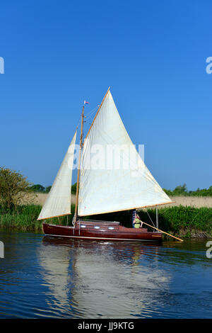 "Hustler 4' Einzelkabine Gaff Schaluppe Segelboot auf dem Fluss Ant at wie Hill Liegeplätze, Ludham, auf der Norfolk Broads mit Turf Moor Entwässerung Mühle in t Stockfoto