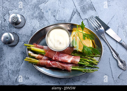 grüner Spargel mit Speck auf einem Tisch Stockfoto