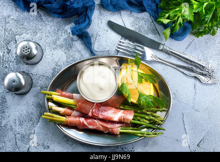 grüner Spargel mit Speck auf einem Tisch Stockfoto