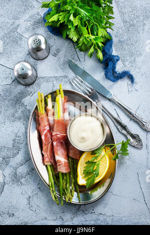 grüner Spargel mit Speck auf einem Tisch Stockfoto