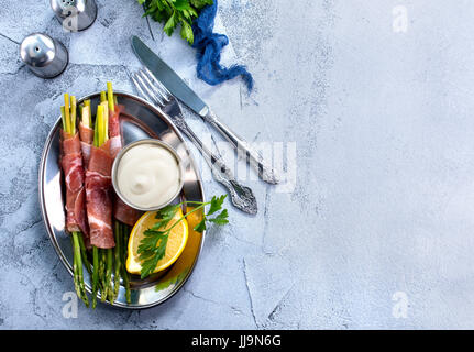 grüner Spargel mit Speck auf einem Tisch Stockfoto