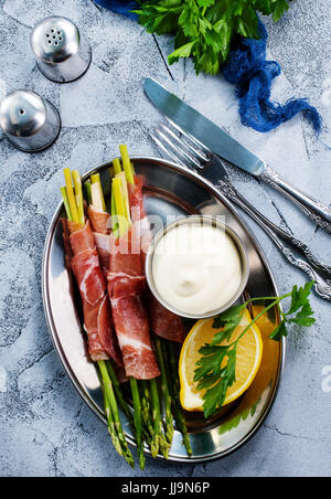 grüner Spargel mit Speck auf einem Tisch Stockfoto