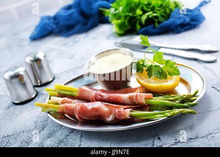 grüner Spargel mit Speck auf einem Tisch Stockfoto