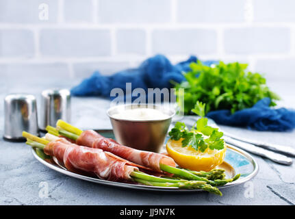 grüner Spargel mit Speck auf einem Tisch Stockfoto