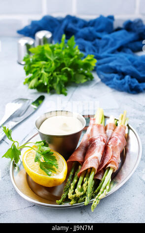 grüner Spargel mit Speck auf einem Tisch Stockfoto
