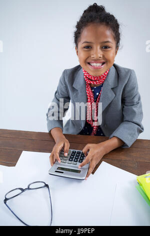 Porträt von lächelndes Mädchen vorgibt als Geschäftsfrau mit Rechner während der Arbeit am Schreibtisch Stockfoto