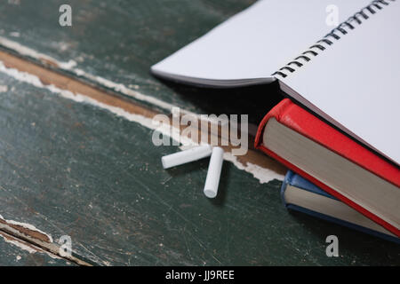 Nahaufnahme von Kreide und Stapel Bücher auf Tisch Stockfoto