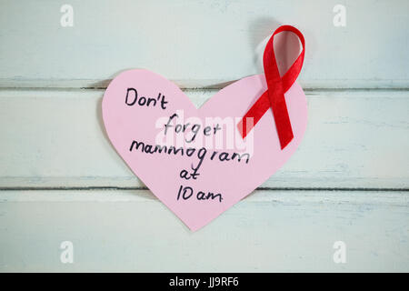 Draufsicht der roten AIDS-Schleife in Herz Form Mahnung über weißen Holztisch Stockfoto