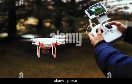 Drone schwebt in der Luft gegen einen holzigen Hintergrund. Stockfoto