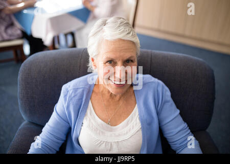 Hohen Winkel Blick lächelnder senior Frau sitzt auf Sessel im Altenheim Stockfoto