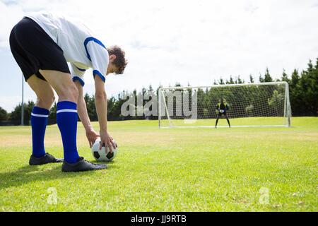 Junge männliche Fußball-Spieler spielen gegen Himmel während der sonnigen Tag Stockfoto