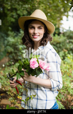 Porträt der Frau trimmen Blumen mit Gartenscheren im Garten an einem sonnigen Tag Stockfoto