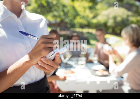 Mittleren Bereich der Kellnerin, die Bestellung auf Notizblock im Restaurant zu schreiben Stockfoto