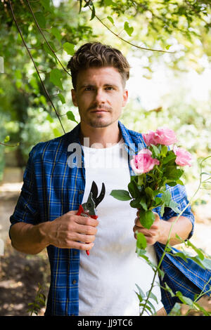 Porträt des Mannes trimmen Blumen mit Gartenscheren im Garten an einem sonnigen Tag Stockfoto