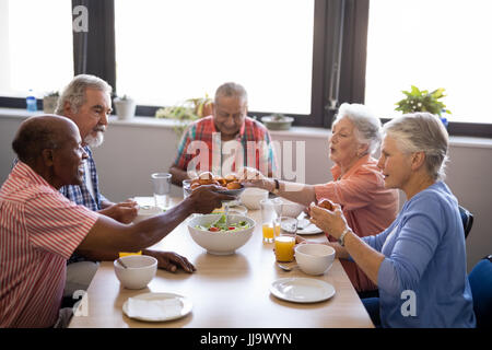 Senior woman geben Essen mit Freunden am Tisch im Pflegeheim Stockfoto