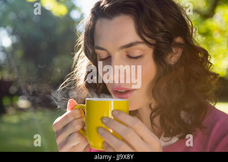 Nachdenkliche Frau mit einer Tasse Kaffee im Garten Stockfoto