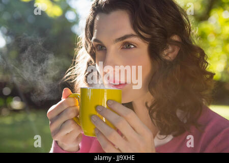 Nachdenkliche Frau mit einer Tasse Kaffee im Garten Stockfoto