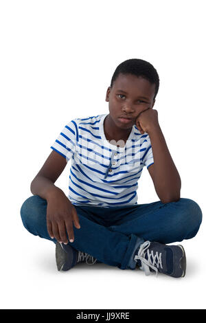 Traurige Junge saß am Boden vor weißem Hintergrund Stockfoto