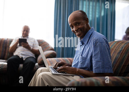 Porträt der ältere Mann mit Laptop von Freund im Pflegeheim Stockfoto