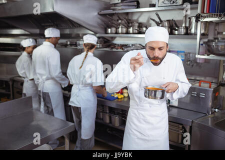 Koch schmeckendes Essen vom Löffel in Küche im restaurant Stockfoto