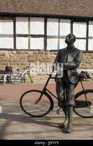 Bronze-Statue von Sir Edward Elgar ruhen auf seinem Fahrrad von Jemma Pearson, 2005 in Hereford Kathedrale, mit der moderne Mensch und Fahrrad im Hintergrund. Stockfoto