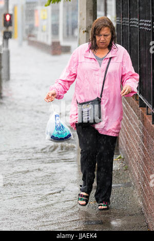 Eine Frau geht durch Flash-Überschwemmungen Wasser auf dem Heimweg nach Starkregen verursachte Sturzfluten, die A525 im Sommer während der Donner und Gewitter, die das Gebiet, Rhyl, North Wales, UK Stockfoto