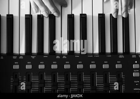 Weibliche Hände sind auf einem Synthesizer. Schwarz-weiß Foto. Blick von oben. Horizontale Foto Stockfoto