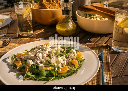 In der Nähe der Sommer Salat serviert draußen auf Garten deck Tisch in der Sonne mit Clementinen, Rakete, Fenchel, Chicoree, Fetakäse, Schottland, Großbritannien Stockfoto