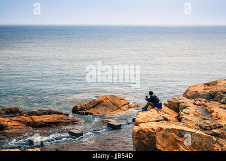 Männliche Touristen sitzen auf einer Klippe auf Stanley, Hong Kong, China Stockfoto