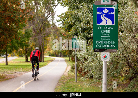 Ein Zeichen für den Ottawa River Weg oder Kapital Weg ist auch Teil der Trans Canada Trail mit einem Radfahrer in Brittania Park vorbei. Stockfoto
