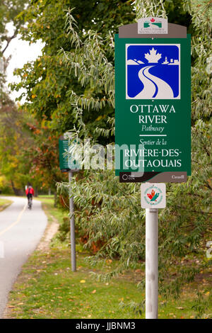 Ein Zeichen für den Ottawa River Weg oder Kapital Weg ist auch Teil der Trans Canada Trail mit einem Radfahrer in Brittania Park vorbei. Stockfoto