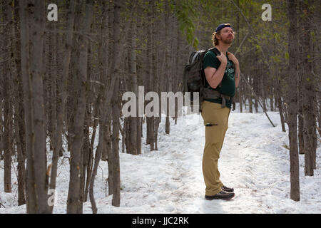 Ein männlicher Wanderer hält in den Wald und Schnee auf dem Taggart Lake Trail im Jackson Hole. Grand Teton Nationalpark, Wyoming Stockfoto