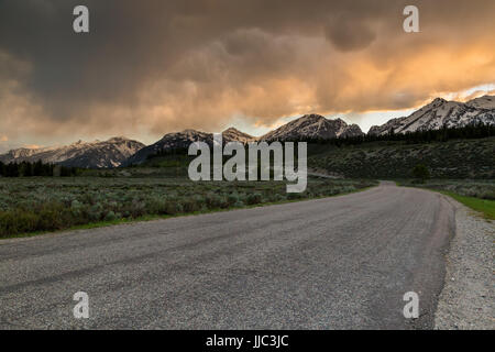 Stürmisches Wetter vorbei über die Teton Mountains beleuchtet von Abendlicht über die Elch-Wilson Road und Jackson Hole. Grand Teton Nationalpark, Wyoming Stockfoto