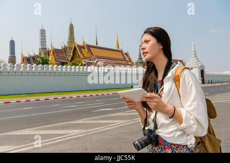 Tablet Computer Frau zu Fuß auf Bürgersteig des grand Palace mit Reise-app oder Google-Earth-Karte während ihrer Reise. chinesische Asiatin entspannend in Bangkok. Stockfoto