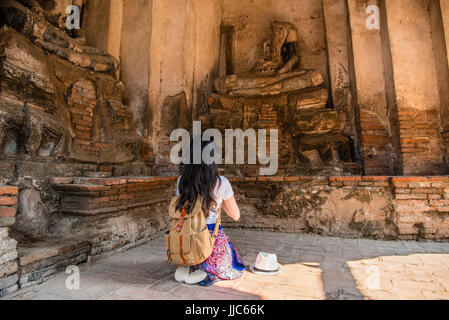 Touristischen Mädchen beten vor gebrochenen Buddha-Statue im Wat Chaiwatthanaram ist alte buddhistische Tempel, Ayutthaya Historical Park, Thailand. Asiatische Frau Stockfoto