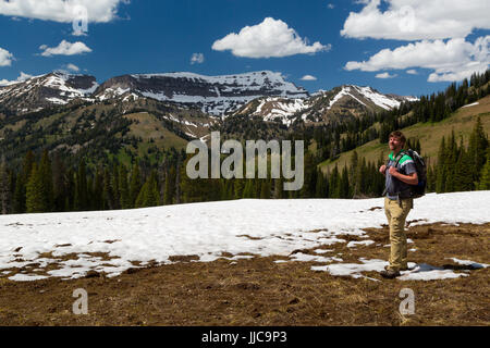 Ein männlicher Wanderer stehend auf Phillips Pass in den Teton Bergen, noch mit Schnee bedeckt. Jedediah Smith Wildnis, Wyoming Stockfoto